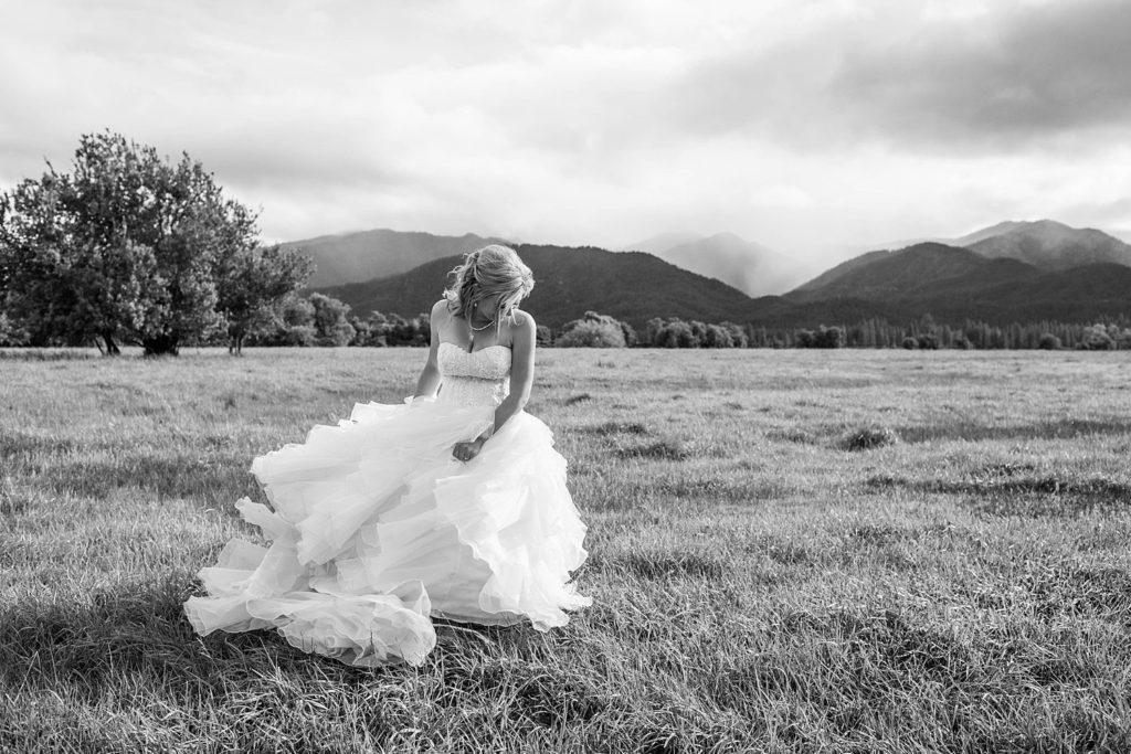 bride with flowy dress twirling in field with stormy skies
