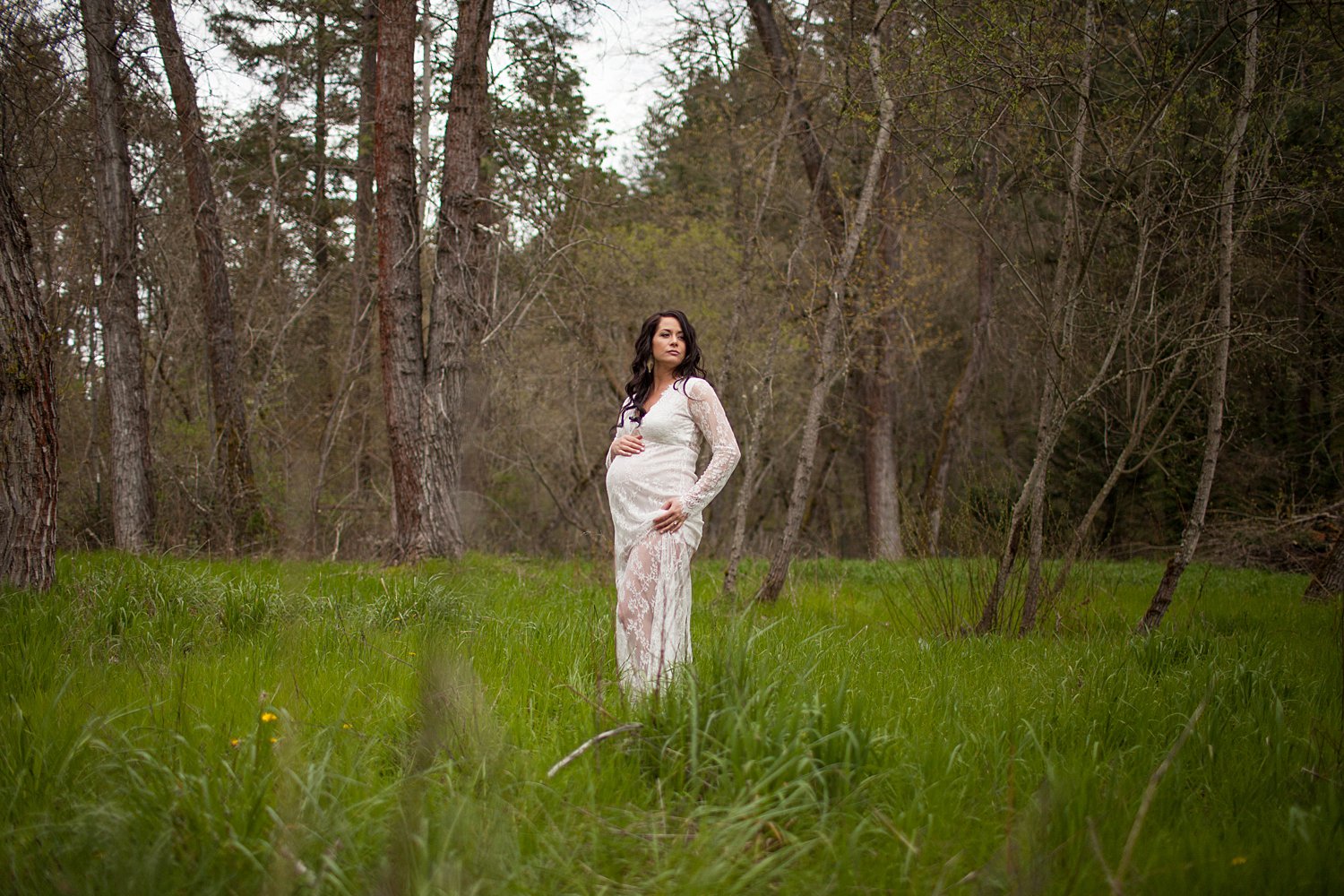 pregnant woman in grass field wearing white lace dress