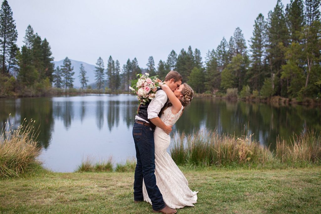 bride and groom kissing by the pond