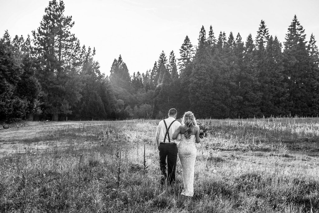 bride and groom embracing and walking away toward pine trees