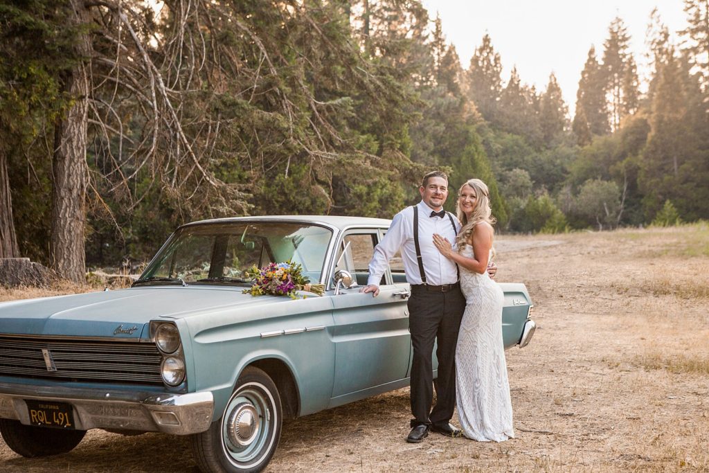 newlyweds by blue vintage car with bouquet