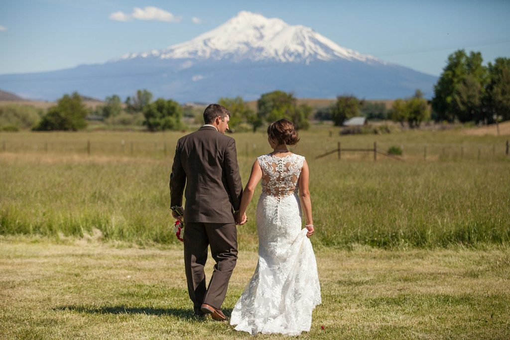 bride and groom holding hands in front of mount shasta