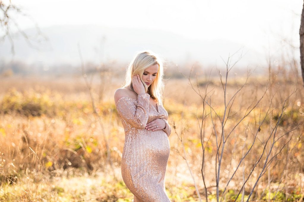 pregnant woman in sequin gold dress at sunset