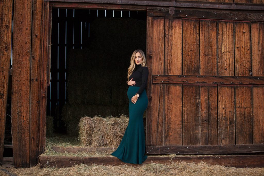 pregnant woman leaning against barn