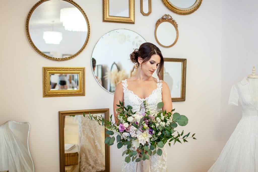 bride holding bouquet in prep room with mirrors