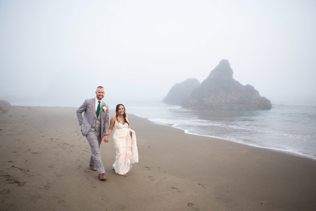 newlyweds holding hands on the rocky beach