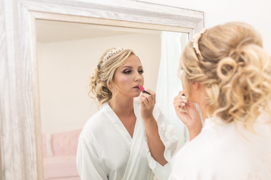 bride putting on lipstick in mirror