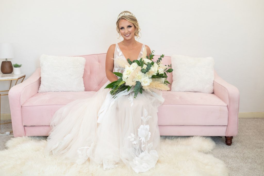 bride on pink couch with bouquet