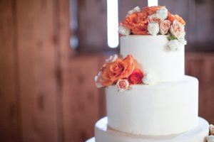white simple wedding cake with orange flowers