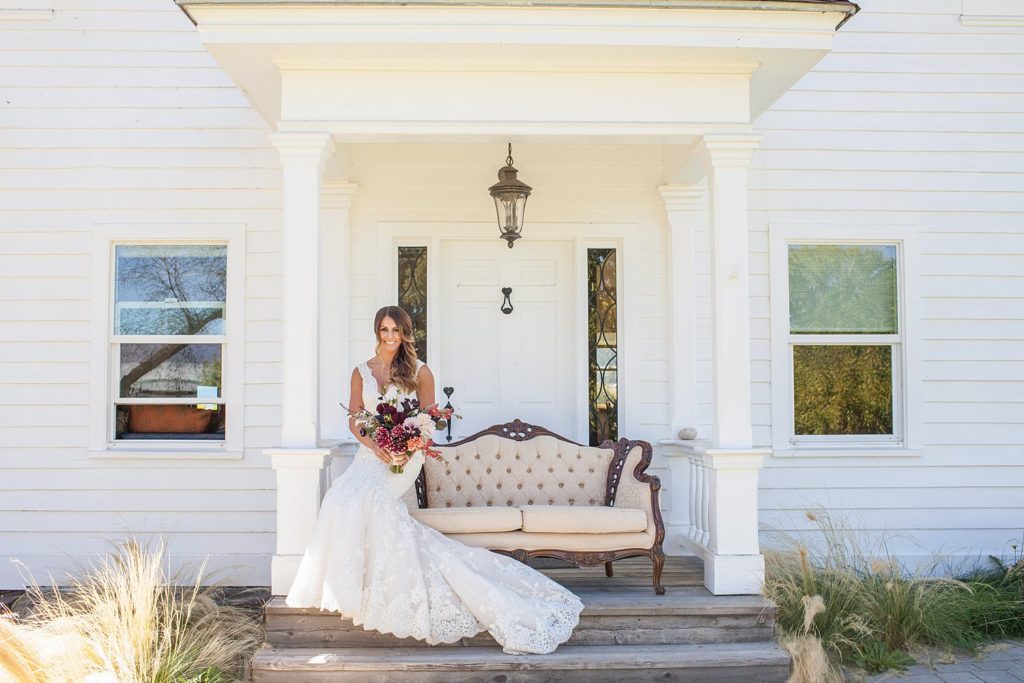 bride holding bouquet sitting on vintage couch