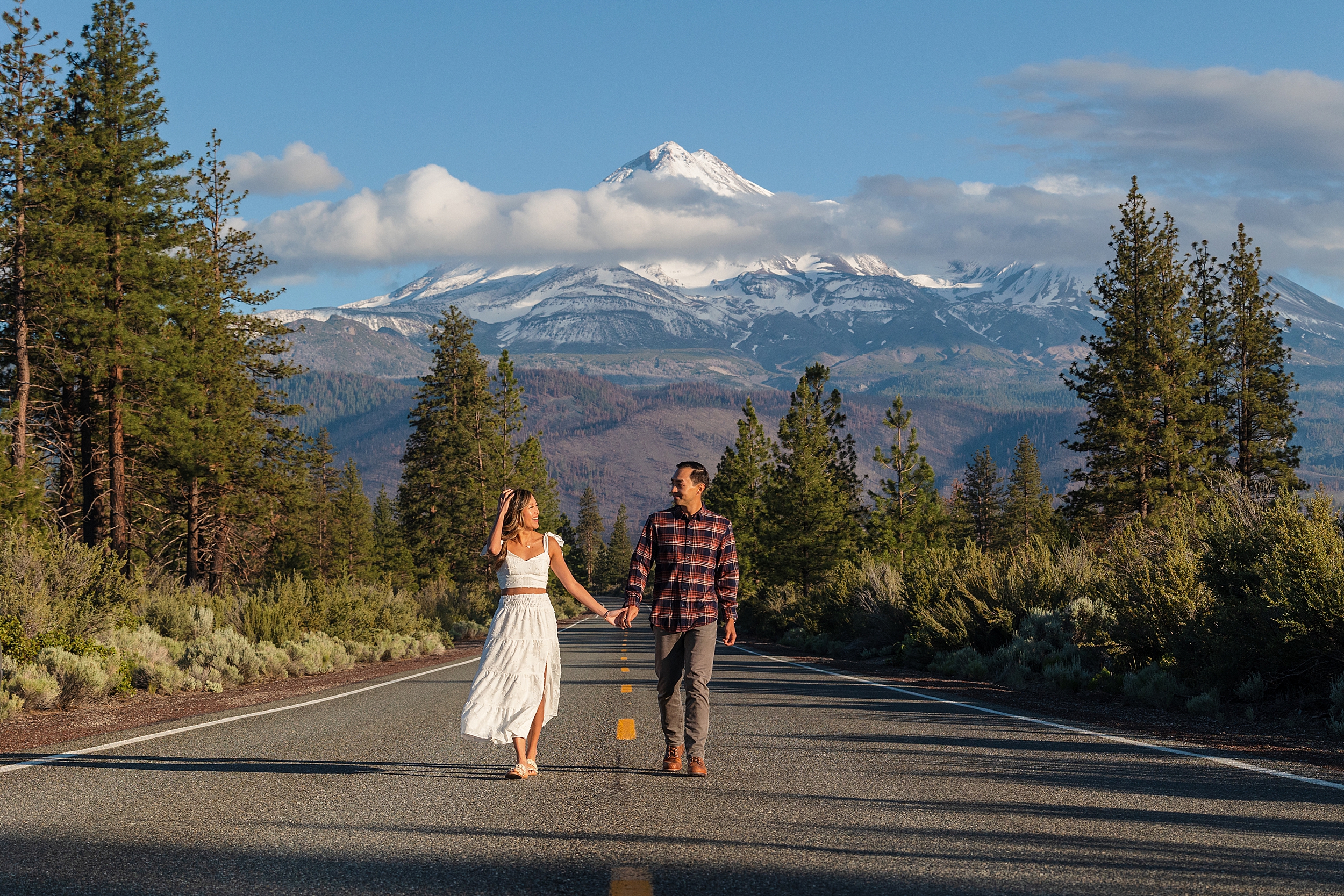 Cute couple walking in the road with Mt. Shasta behind them