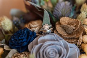 wedding rings sitting on wooden flower bouquet