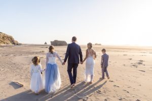 newlyweds and their kids walking on the beach