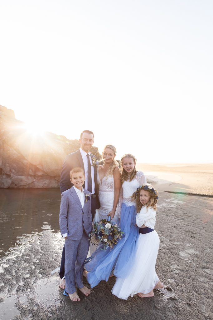 newlyweds with their kids on the beach at sunset