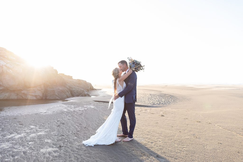 Bride and groom kissing on the beach at sunset in Oregon