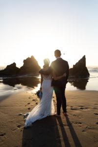 Bride and groom silhouette on the rocky beach in Bandon, Oregon