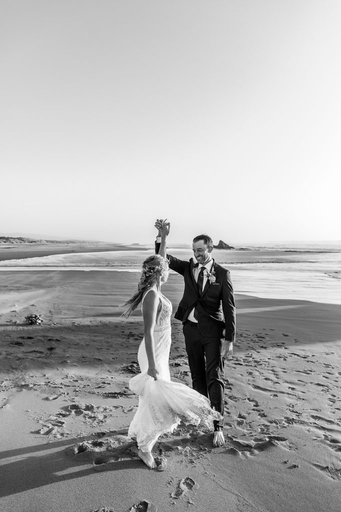 bride and groom dancing on the beach while her dress twirls