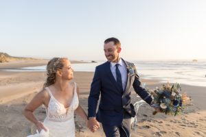 happy newlyweds walking on the beach