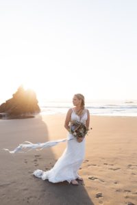 bride holding bouquet on the windy beach