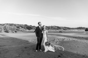 Bride and groom on windy beach at sunset