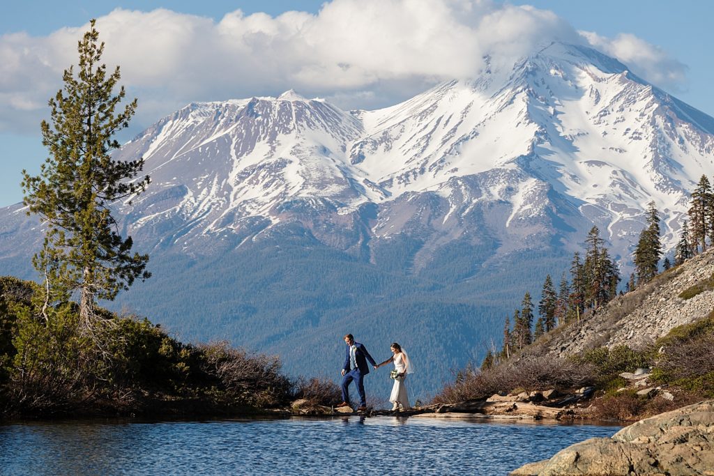 Newlyweds walking along Heart Lake with Mt Shasta views